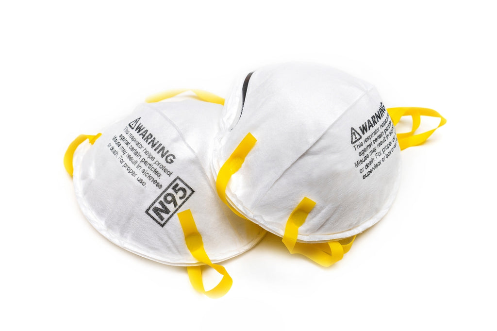 Two N95 masks with yellow adjustable straps on a white background.